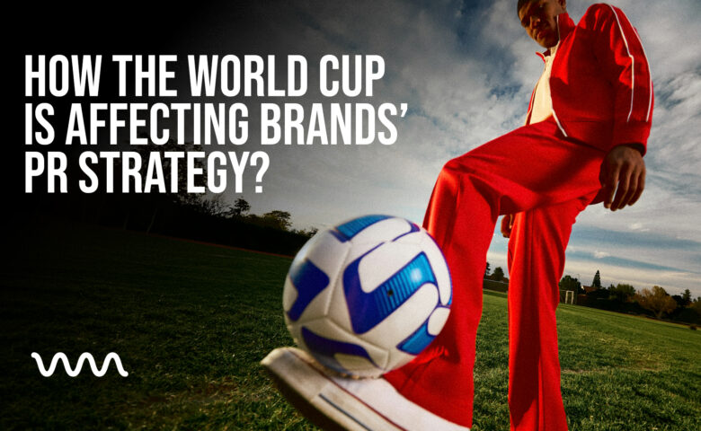 Soccer player in a red tracksuit on a grassy field, about to kick a blue-and-white ball, with the large headline How the World Cup is Affecting Brands’ PR Strategy on the left and a white wave logo bottom-left.
